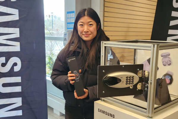 Student holding Samsung Galaxy Watch prize at campus event.