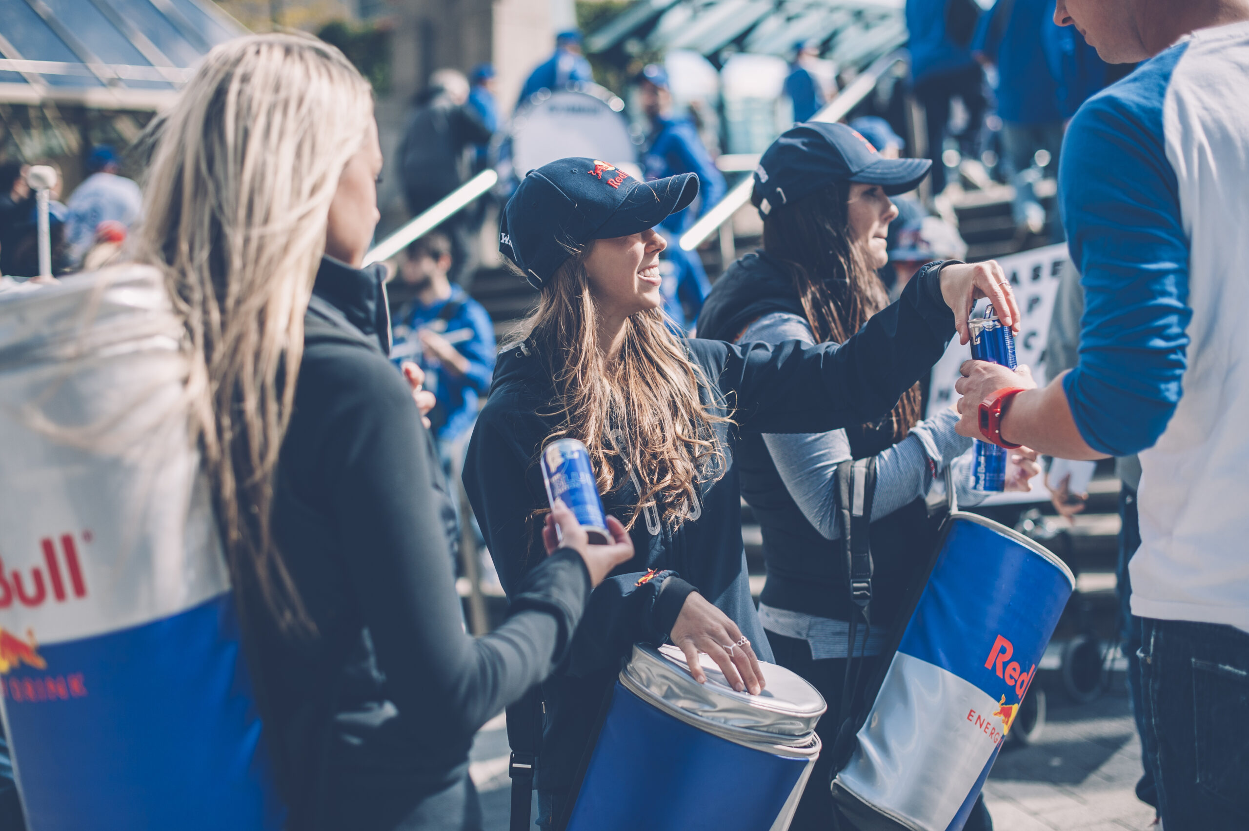 Red Bull brand ambassadors sampling energy drinks at a promotional event.