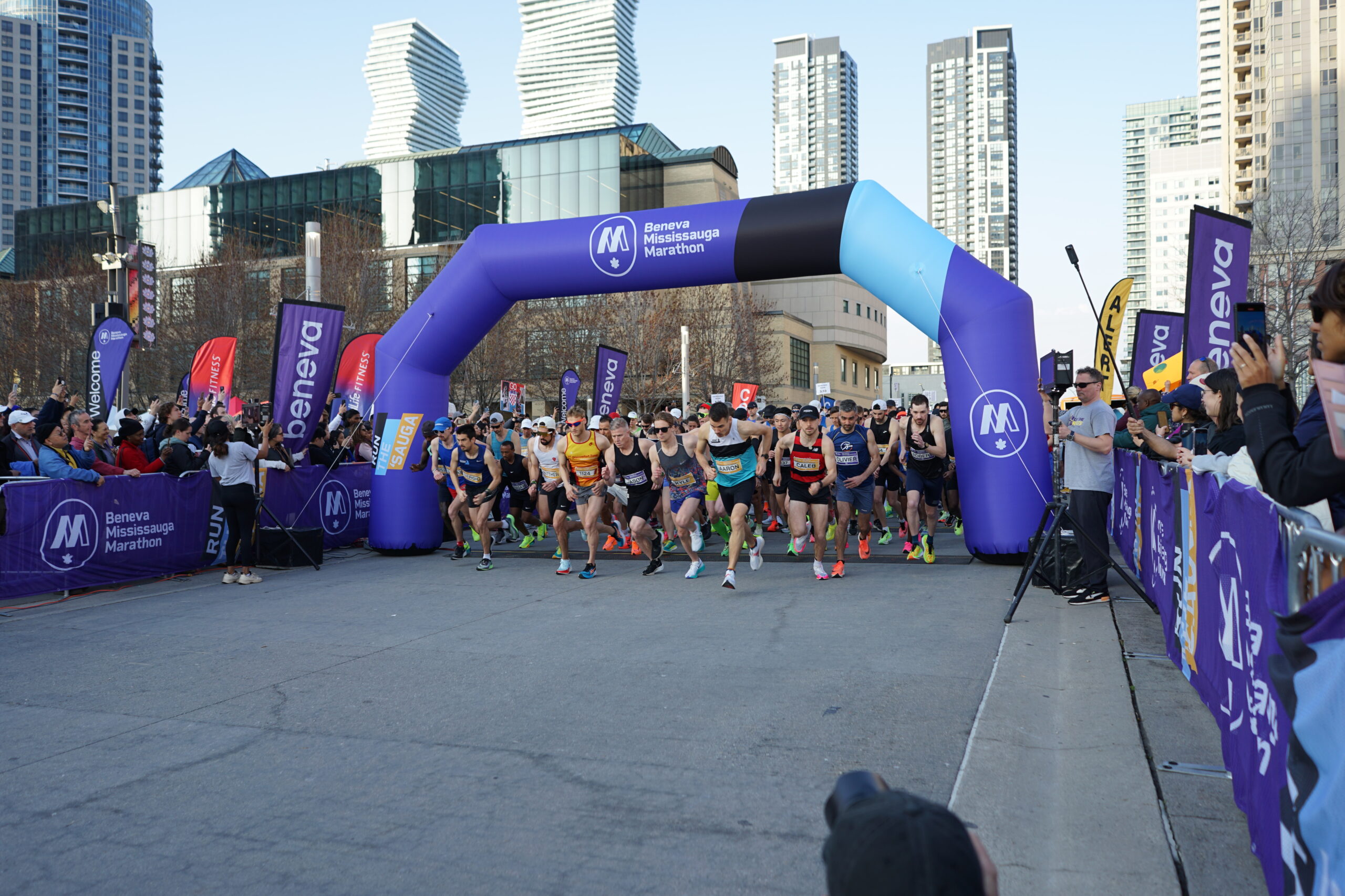 Runners start Beneva Mississauga Marathon with cheering crowd and banners.
